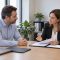 Trabajador y responsable de recursos humanos conversando ante una mesa con carpetas